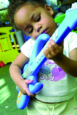 Little girl playing with a toy guitar