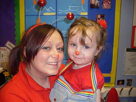 A little girl celebrating Red Nose Day 2009 with a member of the nursery staff
