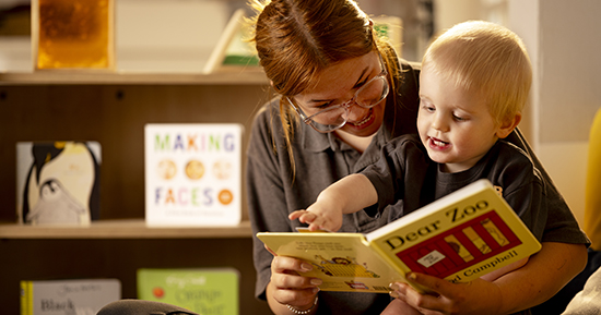 Nursery practioner reading a book with a child.
