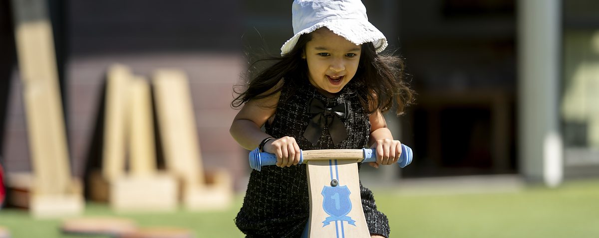 A young child riding a balance bike in the nursery garden.