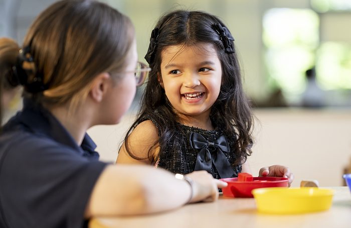 A child sitting at a table with a practitioner at mealtime.