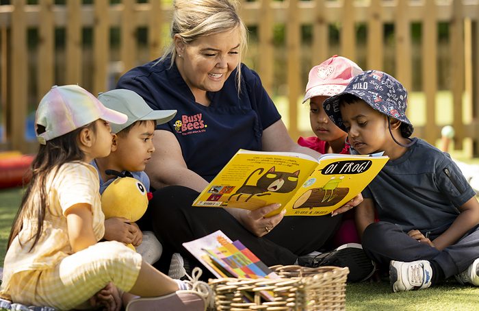 A practitioner reading a story to a group of children in the garden.